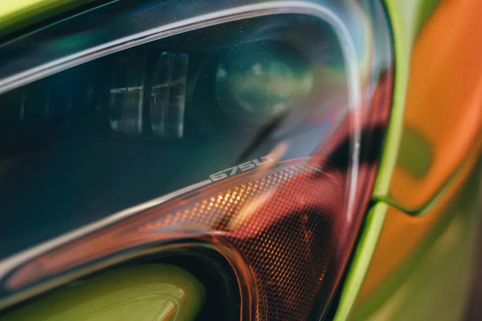 A close-up detail shot of a McLaren 675LT headlight, showcasing the '675LT' branding within the light assembly.