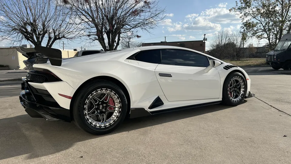 White Lamborghini Huracan with aftermarket drag wheels, large carbon fiber rear wing, and aggressive aero kit.