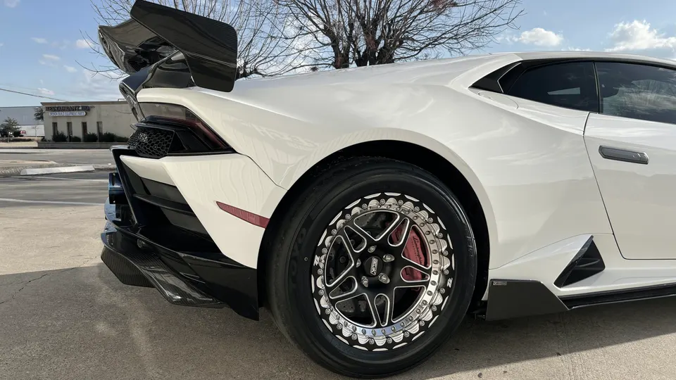 White Lamborghini Huracan with aftermarket drag wheels, large carbon fiber wing, and rear diffuser.