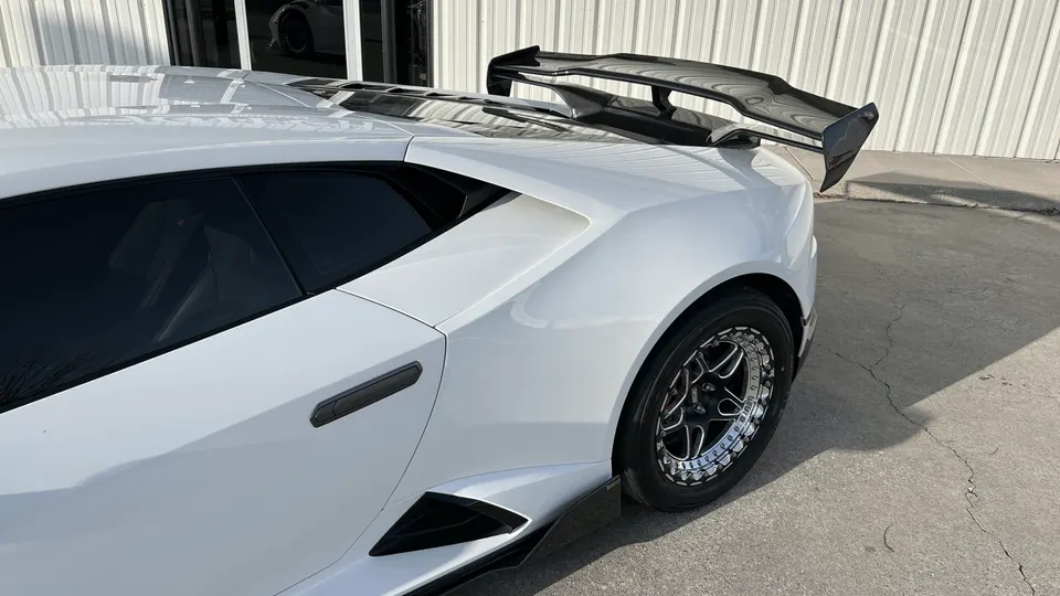 White Lamborghini Huracan with a large carbon fiber rear wing and drag racing wheels parked outside.
