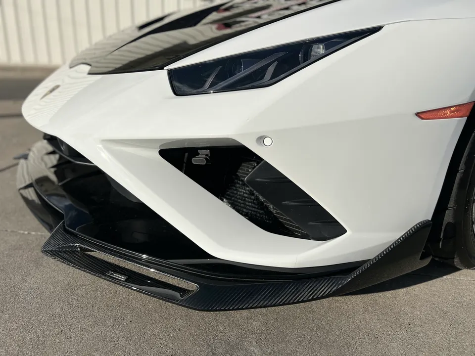 White Lamborghini Huracan with a carbon fiber front splitter, showcasing aggressive exterior aero.