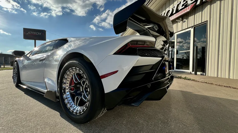 White Lamborghini Huracan with a large aftermarket rear wing and drag wheels parked outside Jotech Motorsports.