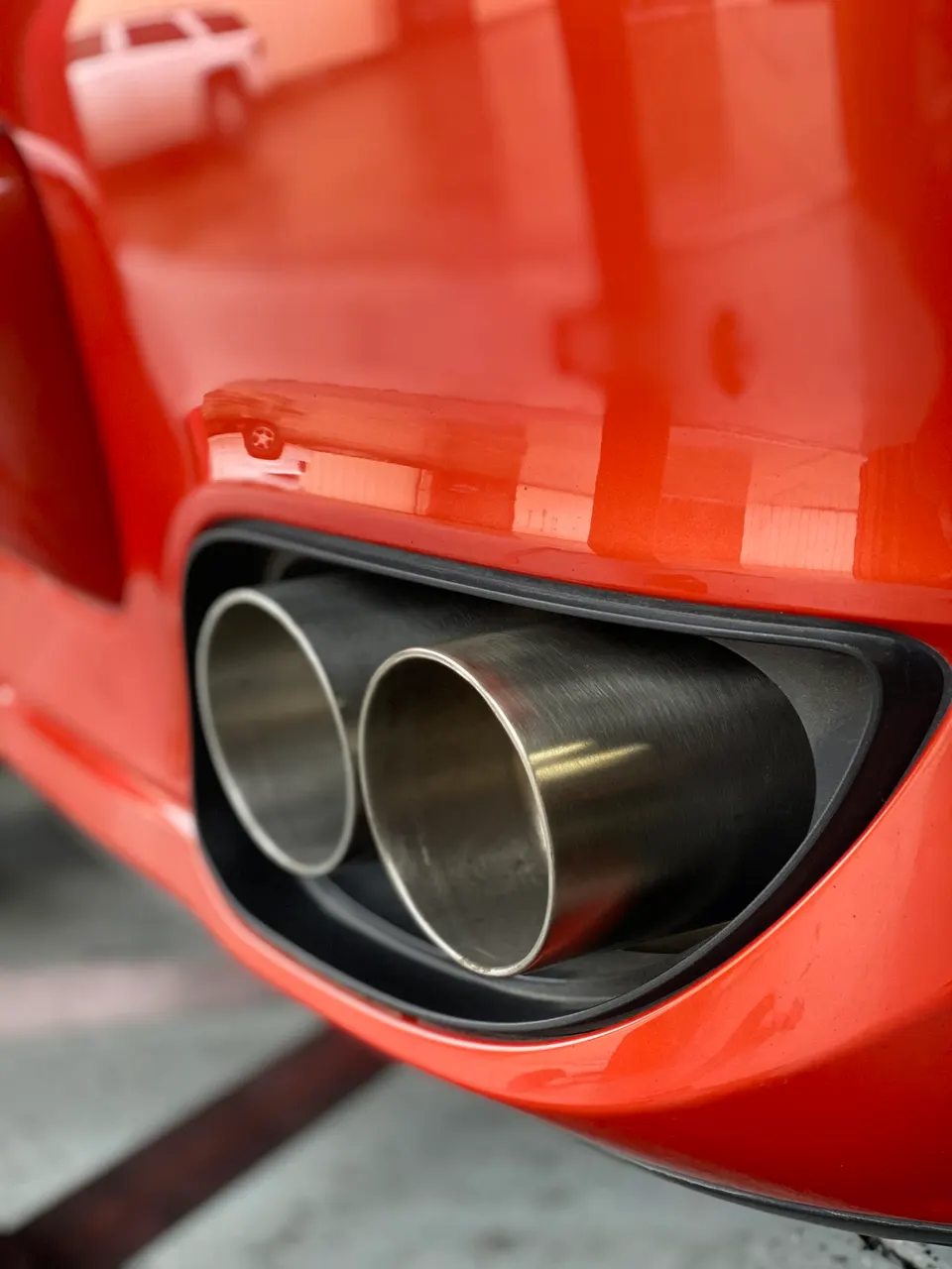 Close-up of dual exhaust tips on a red performance car, showcasing the aftermarket exhaust system.
