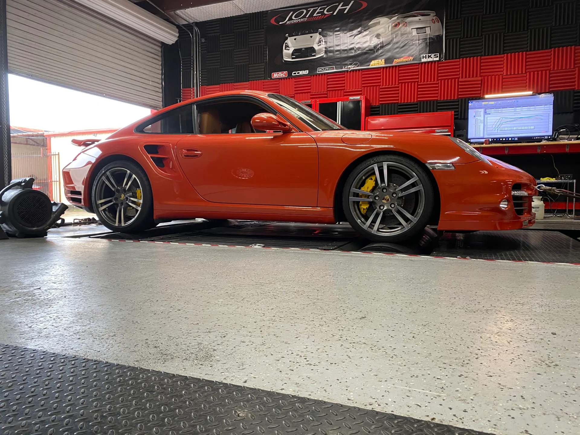 Orange Porsche 911 on a dyno at Jotech Motorsports for performance tuning.