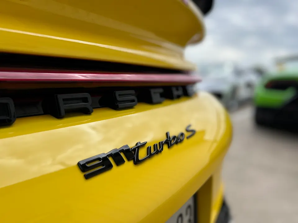 Close-up of the rear of a yellow Porsche 911 Turbo S, showing the black '911 Turbo S' badge.