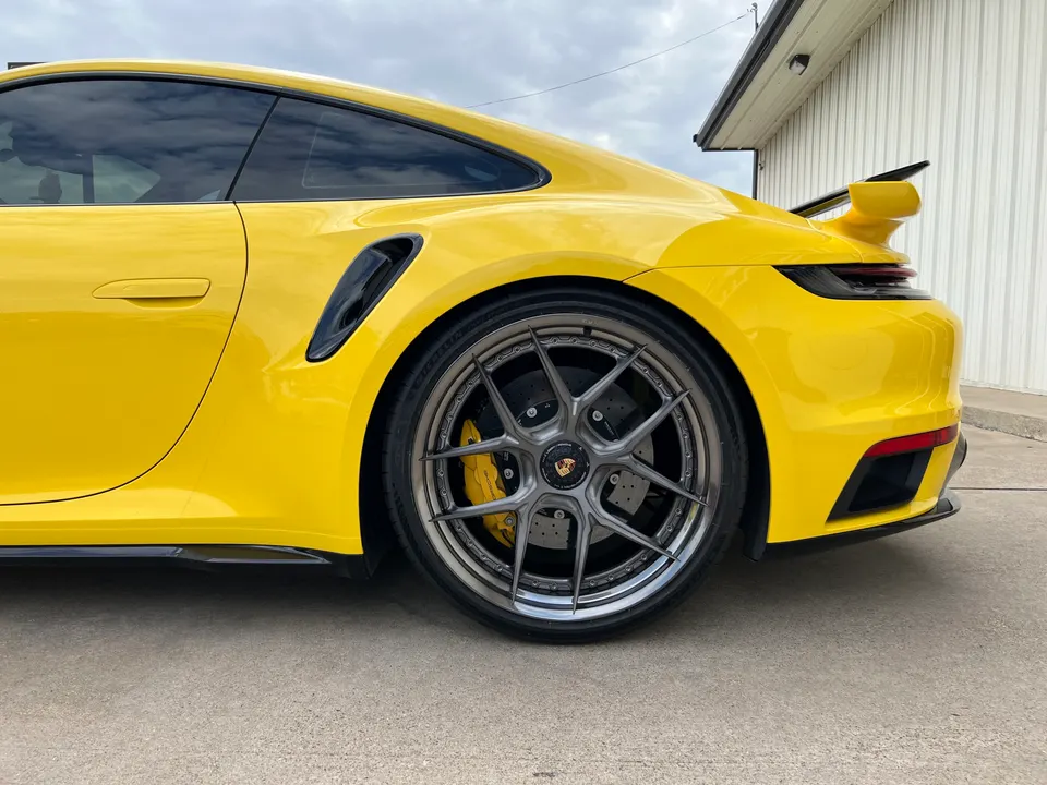 Yellow Porsche 911 with custom multi-spoke wheels, yellow brake calipers, and a large rear wing.