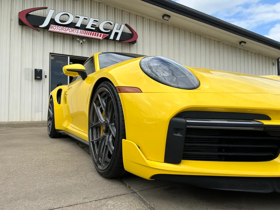 Yellow Porsche 911 parked outside Jotech Motorsports performance tuning shop in Garland, TX.