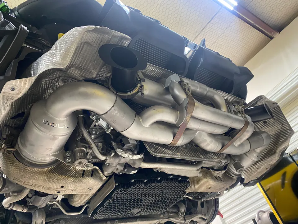 Underside view of a Porsche with a Soul Performance aftermarket exhaust system installed in a shop.