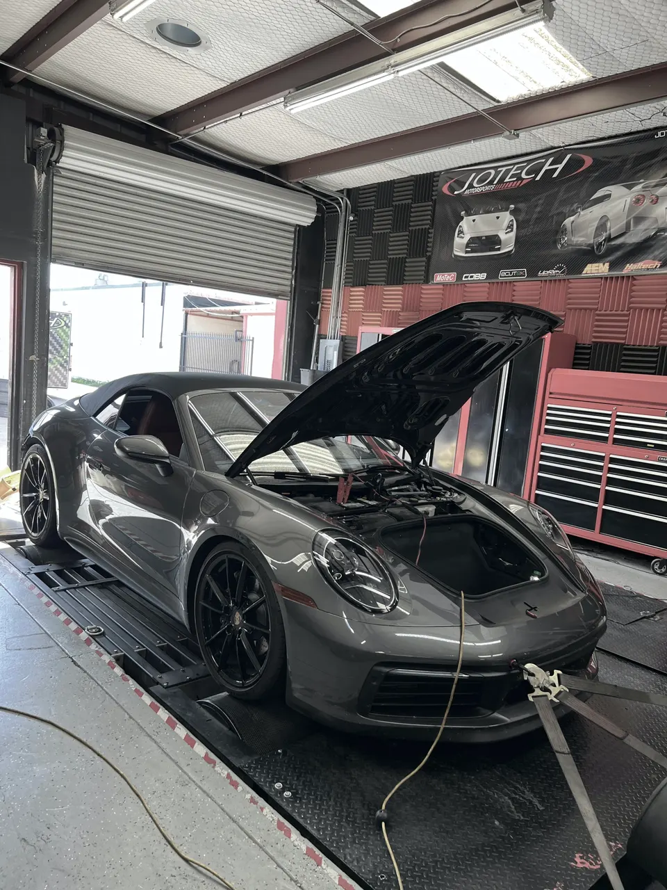 Grey Porsche 911 convertible strapped to a dyno at Jotech Motorsports for performance tuning.
