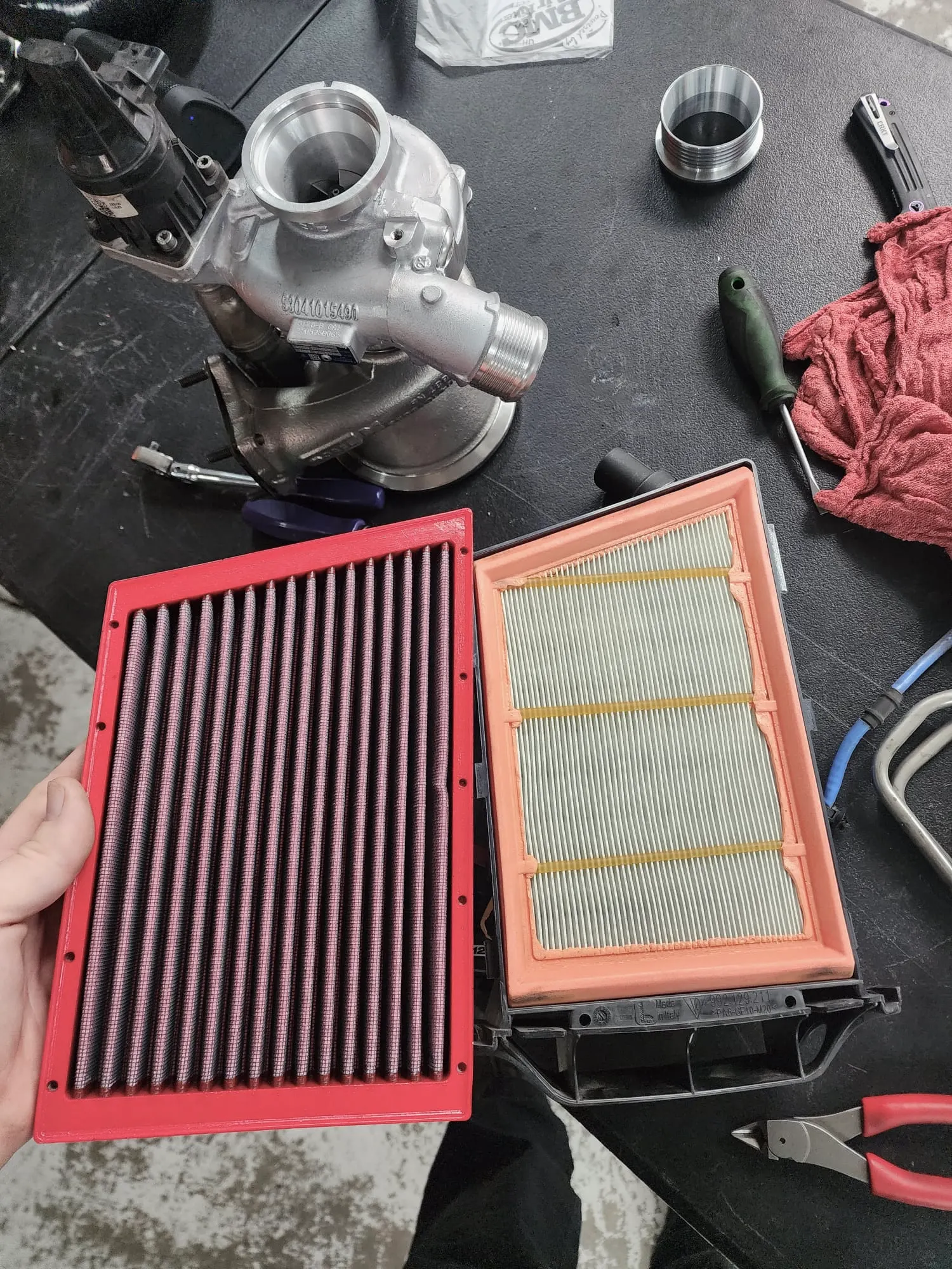 New performance air filter and turbocharger on a workbench in a performance tuning shop, ready for installation.