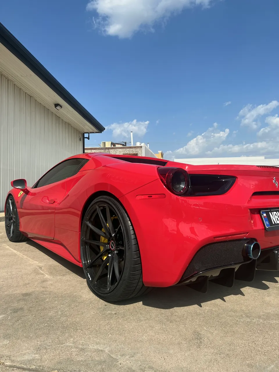 Red Ferrari 488 parked outdoors, showcasing aftermarket wheels, carbon fiber diffuser, and titanium exhaust.