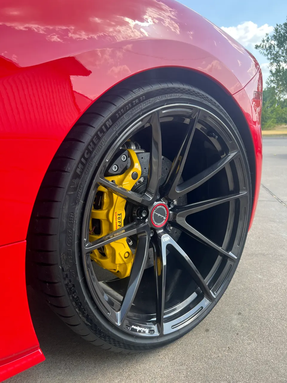 Close-up of a red car's black multi-spoke wheel with Michelin tire and yellow Ferrari brake caliper.