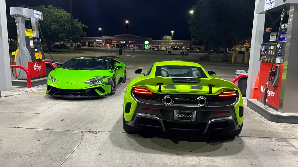 Two neon green supercars, a Lamborghini Huracan and a McLaren, parked at a Kroger gas station at night.