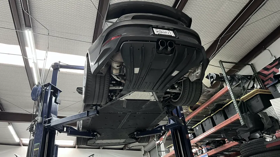 A Porsche 911 GT3/RS on a lift in a shop, showcasing its rear exhaust system and diffuser.