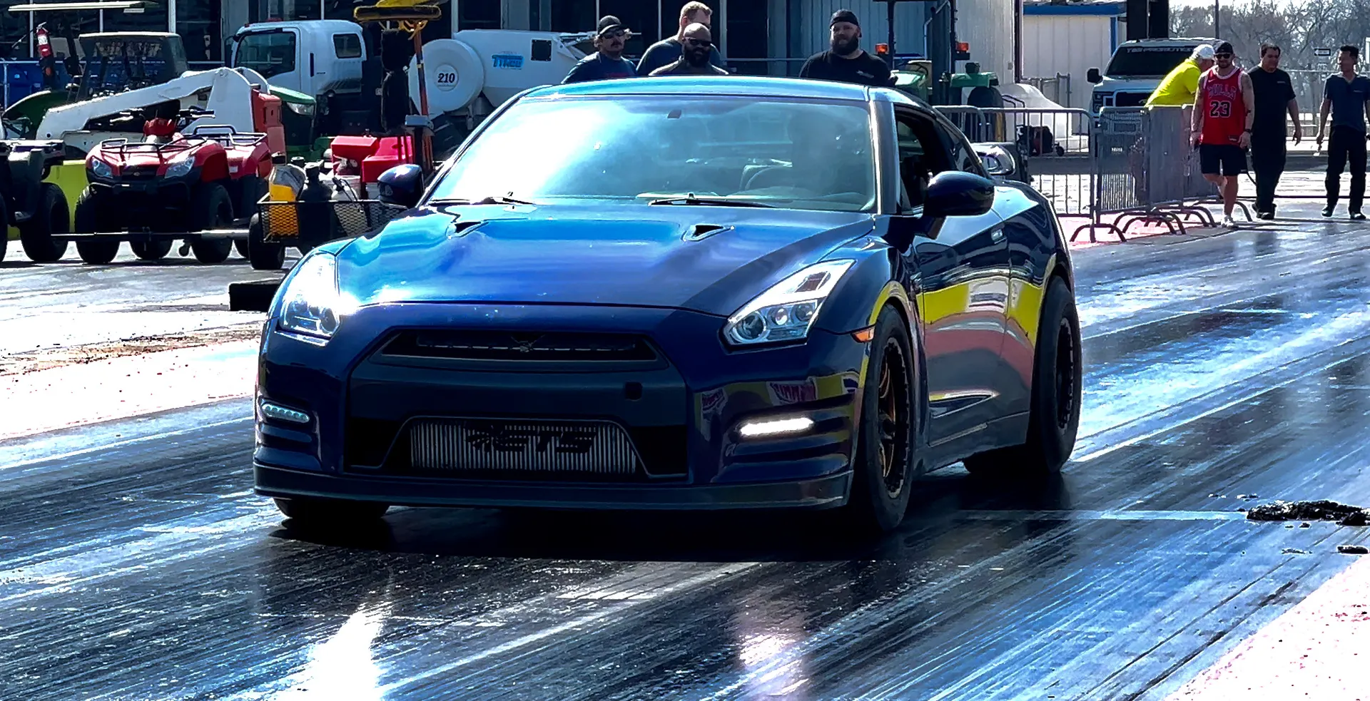 Blue Nissan GT-R with an aftermarket intercooler on a drag strip, ready for a race.
