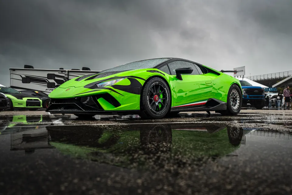 Bright green Lamborghini Huracan drag car with aftermarket wheels and aero parked on a wet track.