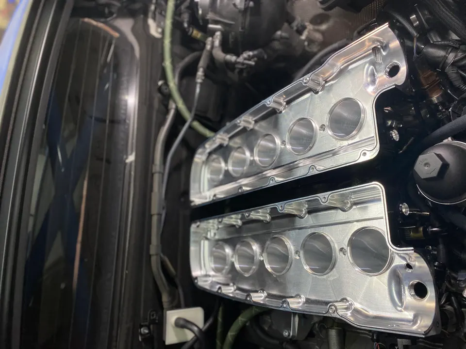 Close-up of custom billet intake manifold runners being installed in a high-performance engine bay.