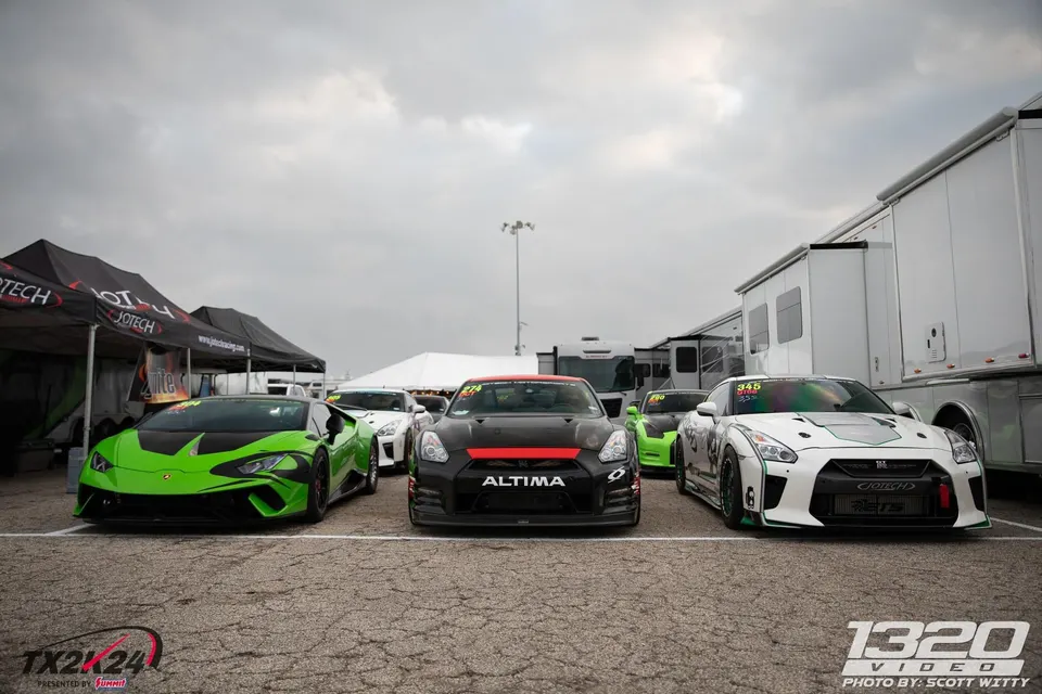 A line of high-performance Lamborghini Huracan and Nissan GT-R race cars parked in the paddock at TX2K24.