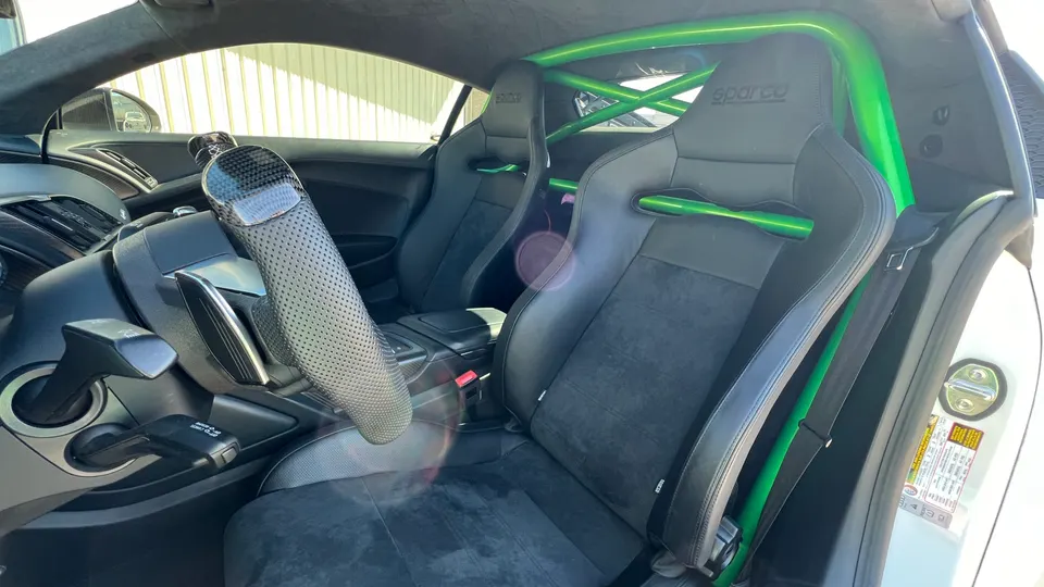 Performance car interior with bright green roll cage, Sparco racing seats, and a carbon fiber steering wheel.