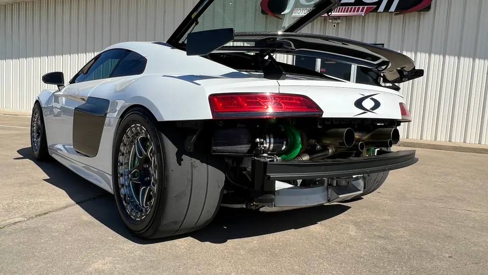 White Audi R8 with exposed rear engine bay showcasing a large turbocharger, custom exhaust, drag tires, and a rear wing.