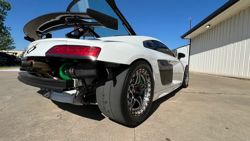 White Audi R8 with rear bumper removed showcasing a large turbocharger, custom exhaust, carbon fiber wing, and drag radial tires.