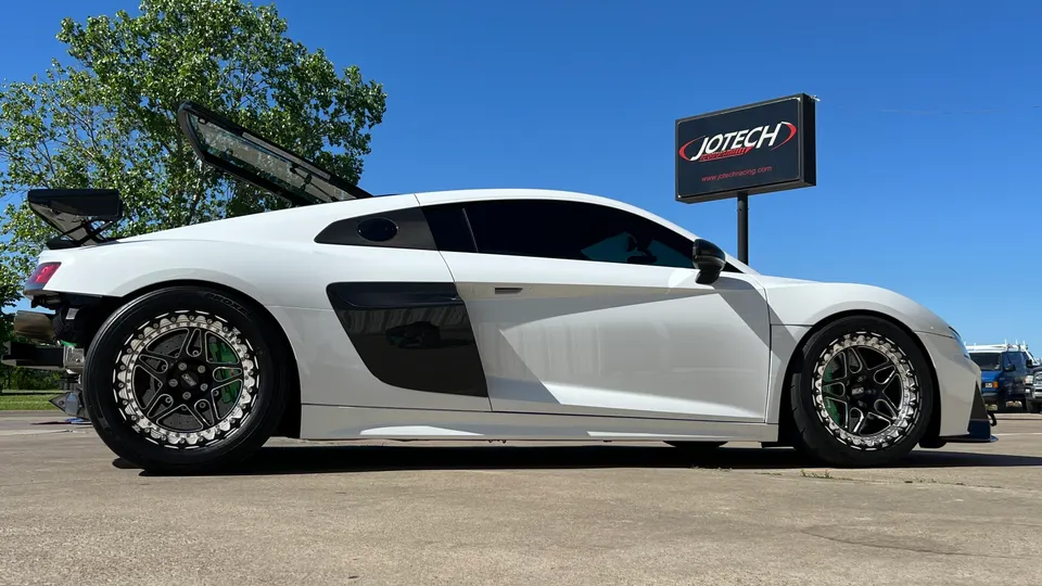 White Audi R8 with aftermarket drag wheels and a large rear wing parked outside Jotech Motorsports.