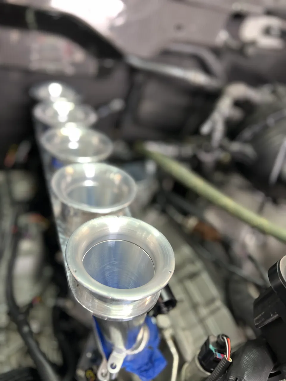 Close-up of individual throttle bodies or velocity stacks installed in a performance car engine bay.
