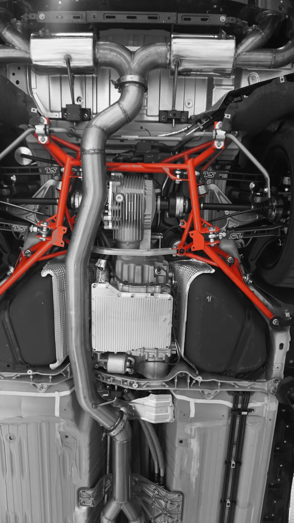 Detailed view of a performance car's undercarriage, showcasing aftermarket exhaust, differential, and red chassis bracing.