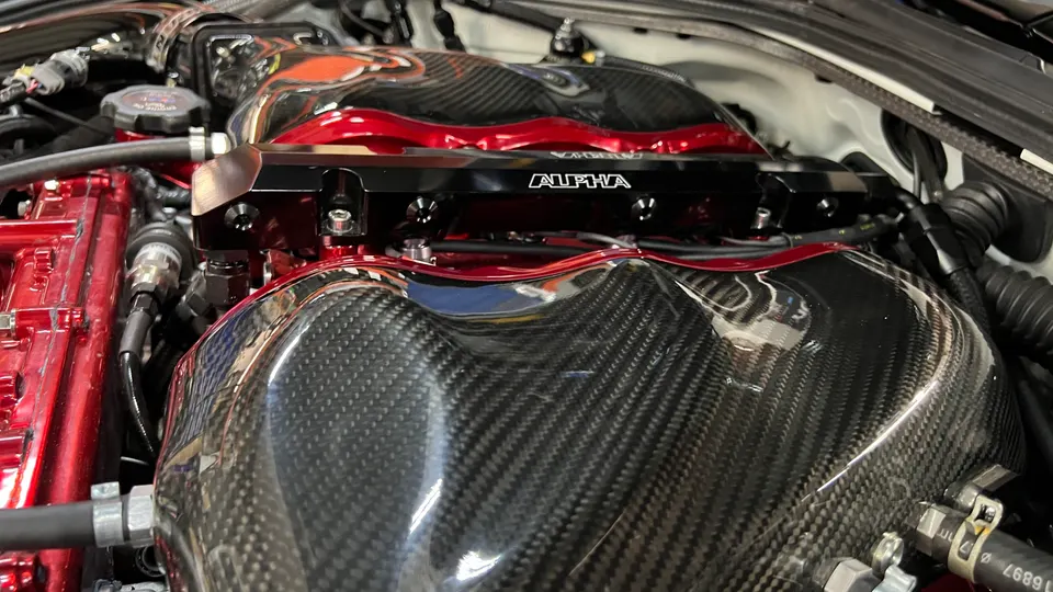 Close-up of a high-performance engine bay featuring carbon fiber intake manifolds and Alpha Performance fuel rails.