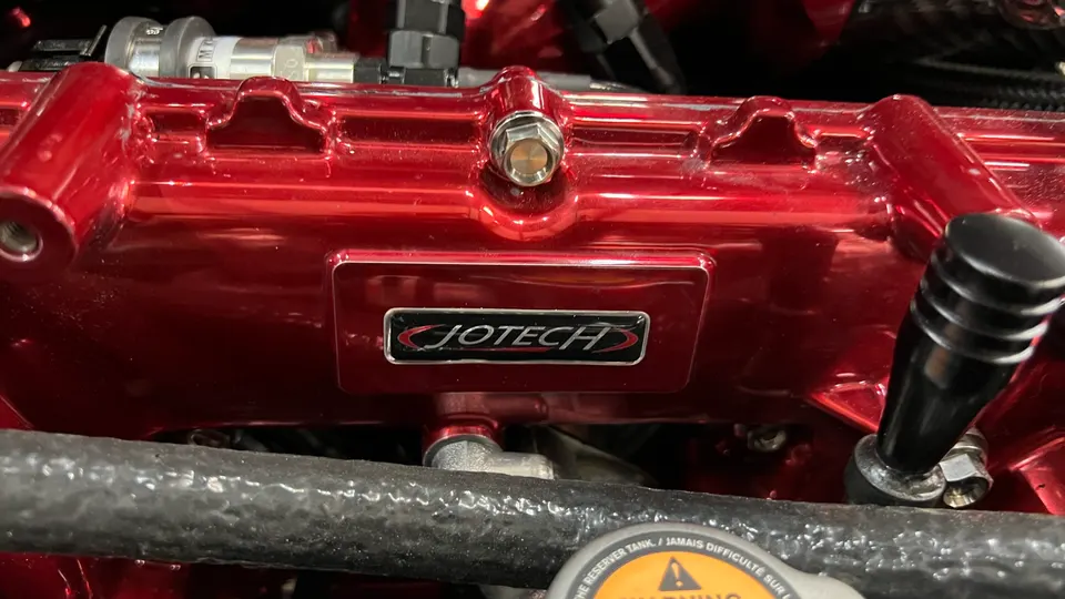 Close-up of a red Jotech valve cover in an engine bay, showcasing custom engine internals.