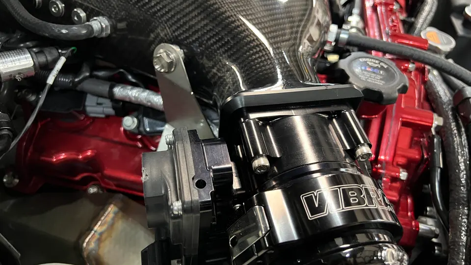 Close-up of a custom engine bay featuring a carbon fiber intake and Vibrant Performance blow-off valve.