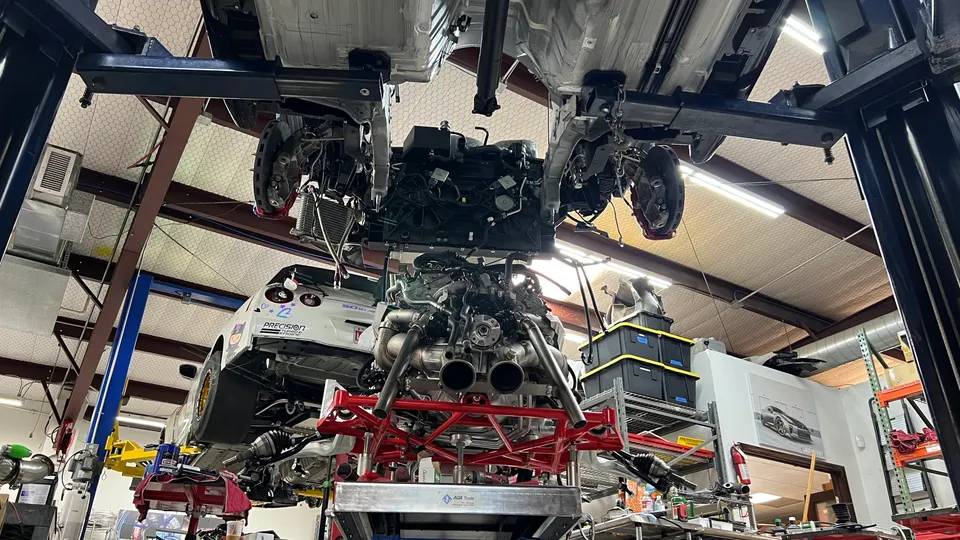 A Nissan GT-R on a lift in a performance shop with its engine and exhaust system removed and on a stand.