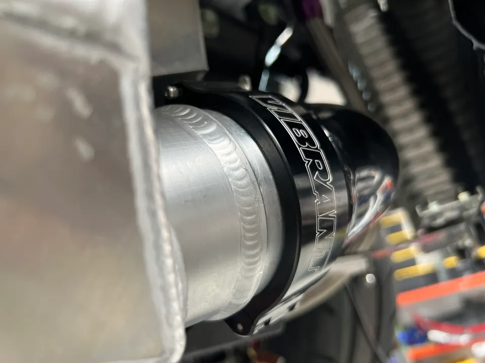 Close-up of Vibrant Performance aluminum boost piping with visible welds in a performance shop.