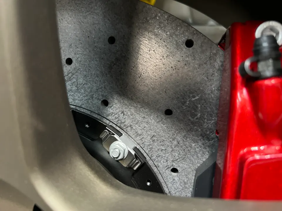 Close-up of a drilled performance brake rotor and red caliper visible through a wheel spoke.
