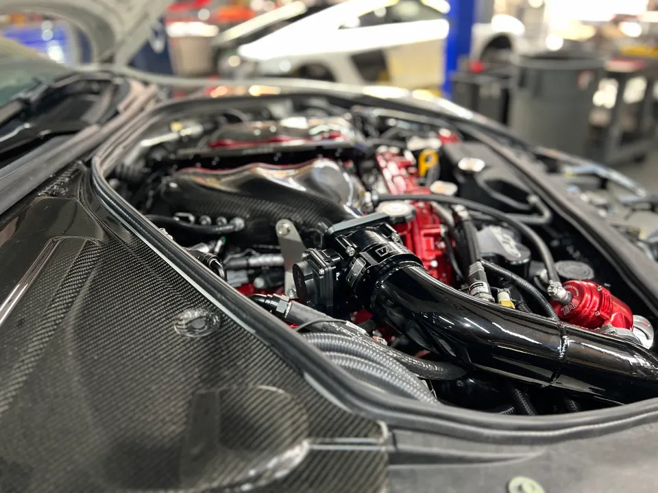 Jotech Motorsports built GT-R engine bay with carbon fiber components, aftermarket boost piping, and a red blow-off valve.