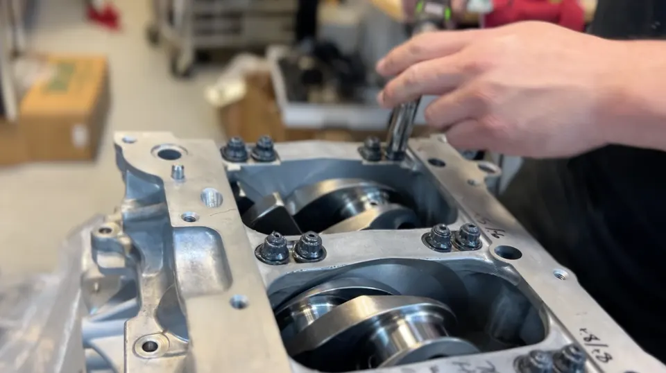 Mechanic assembling an engine block with a crankshaft in a performance tuning shop.