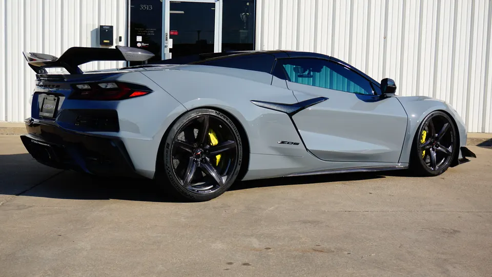 Grey Chevrolet Corvette C8 Z06 with aftermarket wheels, large carbon fiber rear wing, and aero kit parked outside.