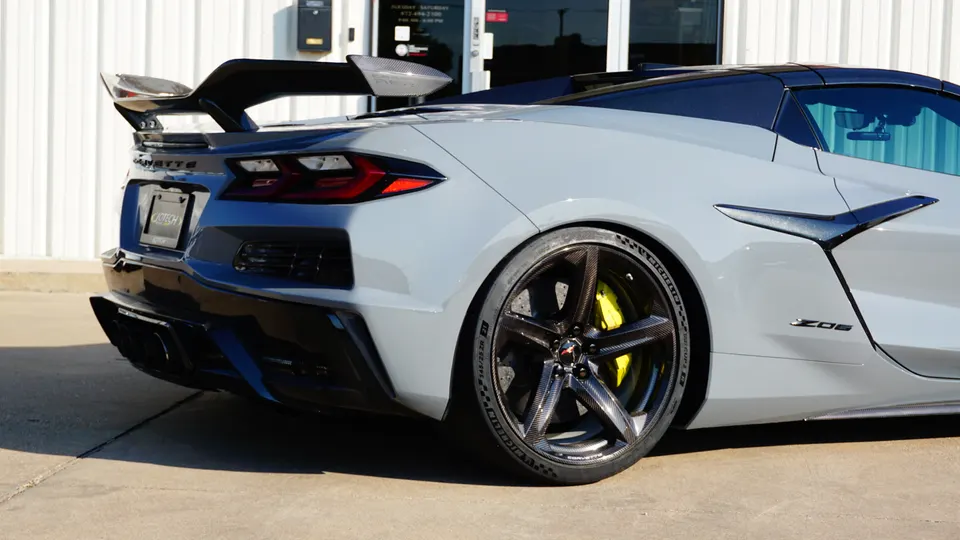 Rear view of a grey Chevrolet Corvette C8 Z06 with a large carbon fiber wing, carbon wheels, and yellow brake calipers.
