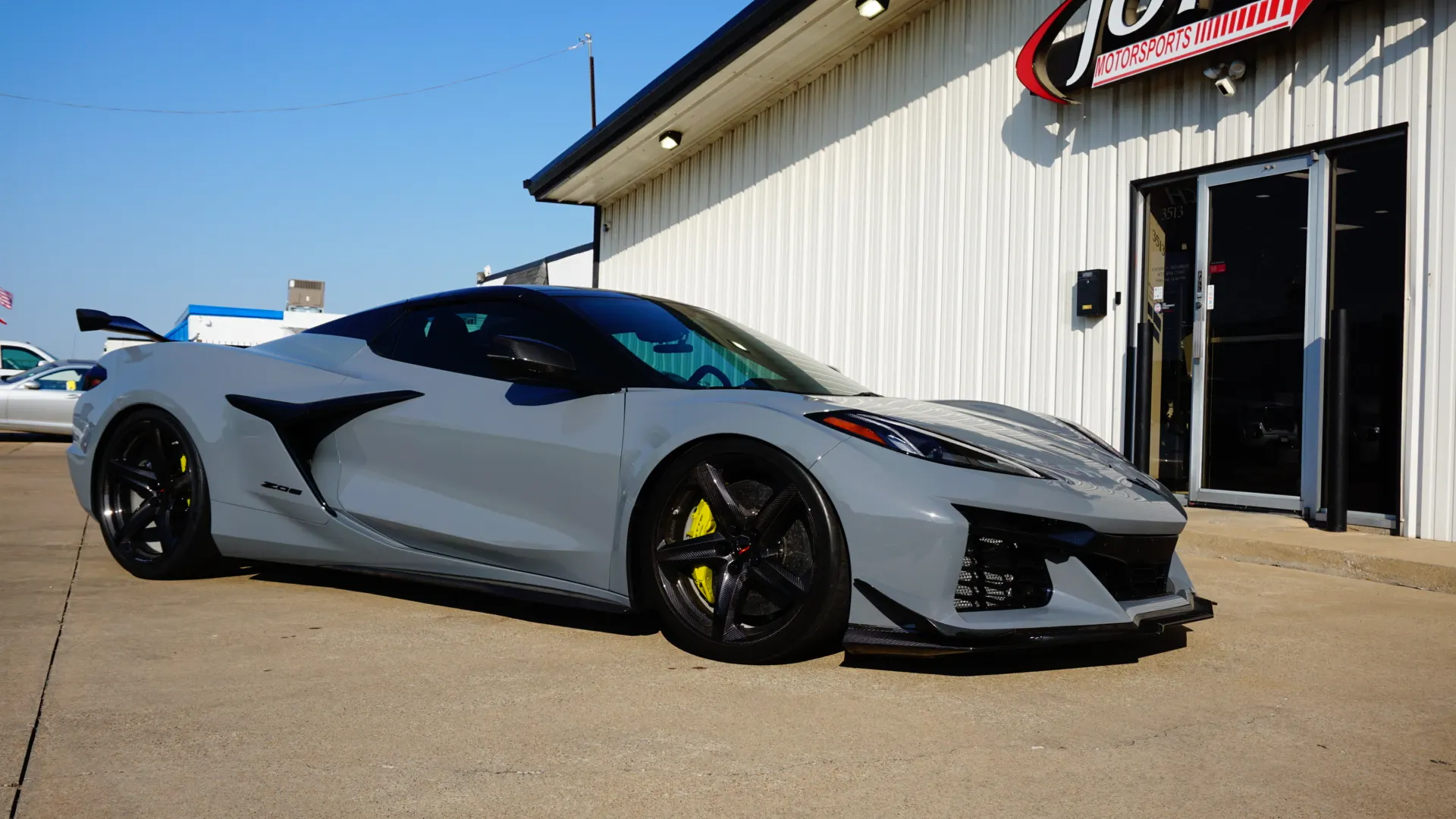 A grey Corvette Z06 with black wheels and yellow calipers parked outside Jotech Motorsports.