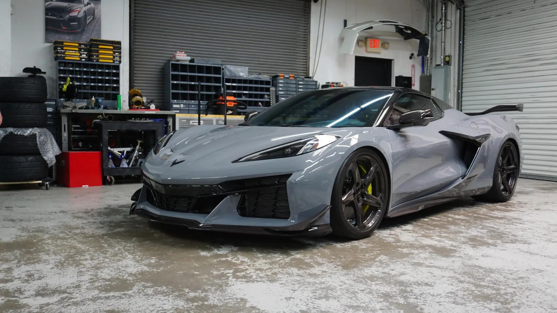 A grey Chevrolet Corvette C8 Z06 with carbon fiber aerodynamic parts parked in a performance tuning shop.