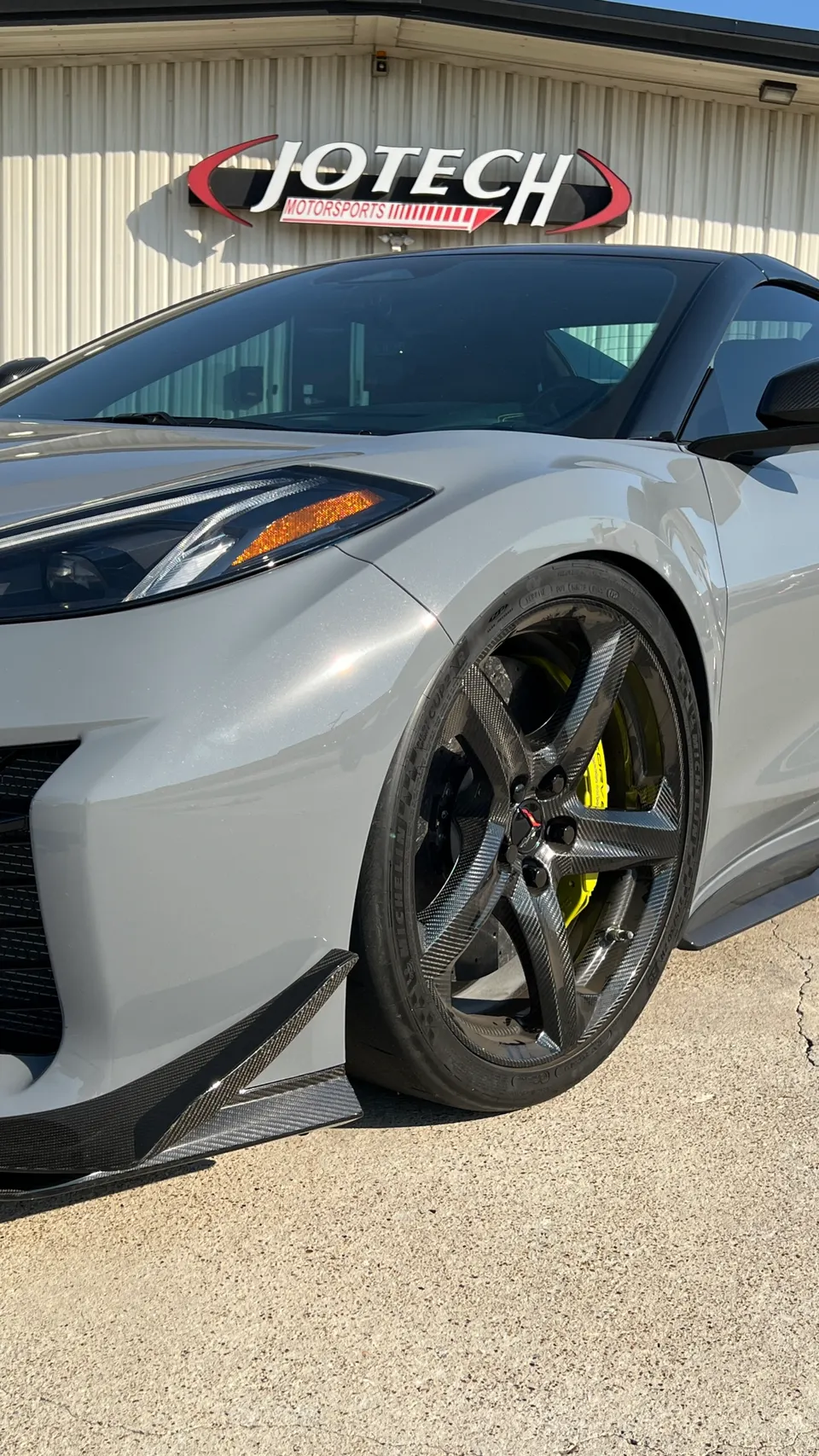 Grey Chevrolet Corvette C8 with carbon fiber wheels, yellow brake calipers, and carbon fiber aero parked outside Jotech Motorsports.