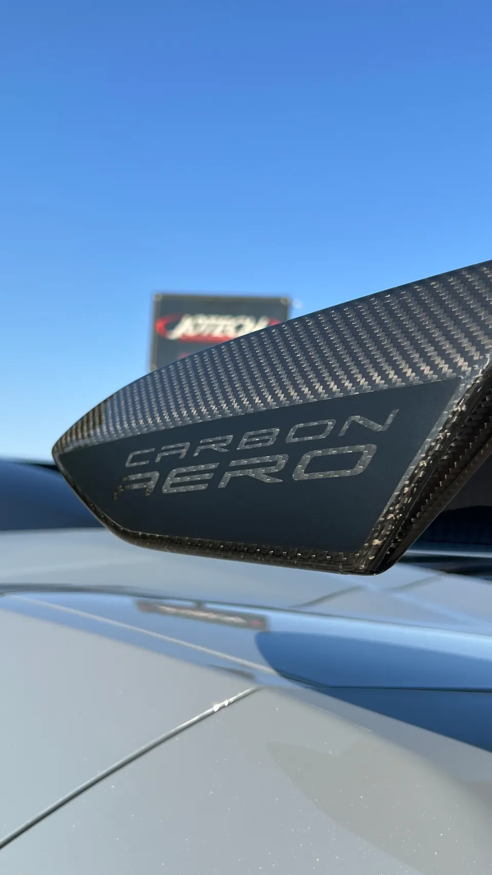 Close-up of a carbon fiber aerodynamic wing with 'CARBON AERO' text, likely from Jotech Motorsports