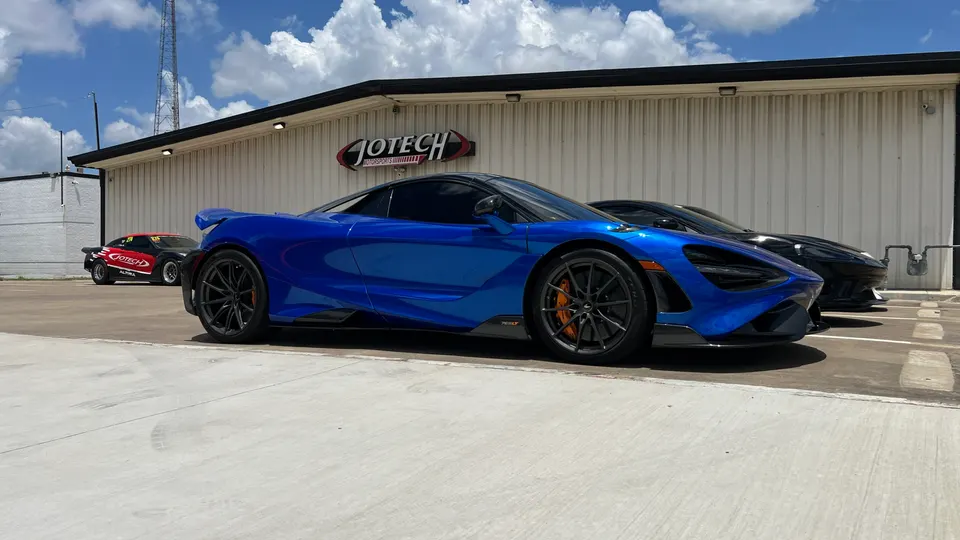Blue McLaren 720S and other performance cars parked outside Jotech Motorsports tuning shop.