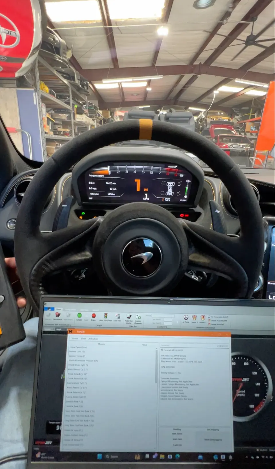 A McLaren interior with a laptop displaying tuning software in a performance shop.
