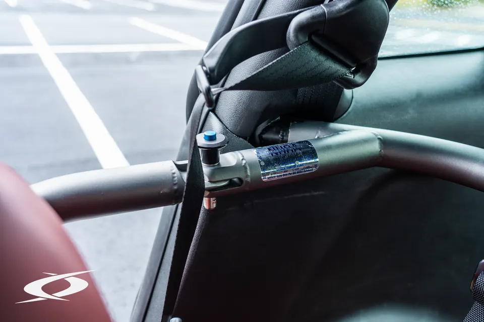 Close-up of a roll bar and racing harness in a performance car's interior, highlighting safety features.