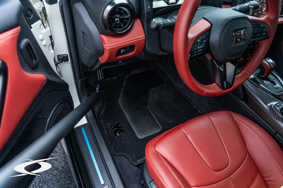 Detailed view of a Nissan GT-R interior with red leather seats, steering wheel, and carbon fiber trim.