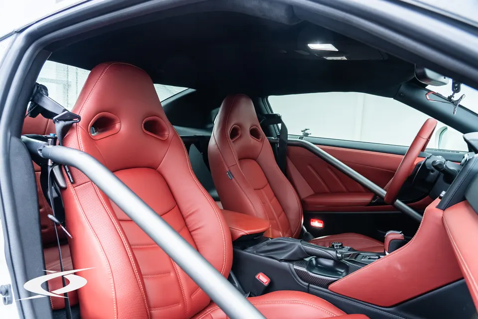 Interior view of a Nissan GT-R with red sport seats and a custom roll bar for enhanced safety.