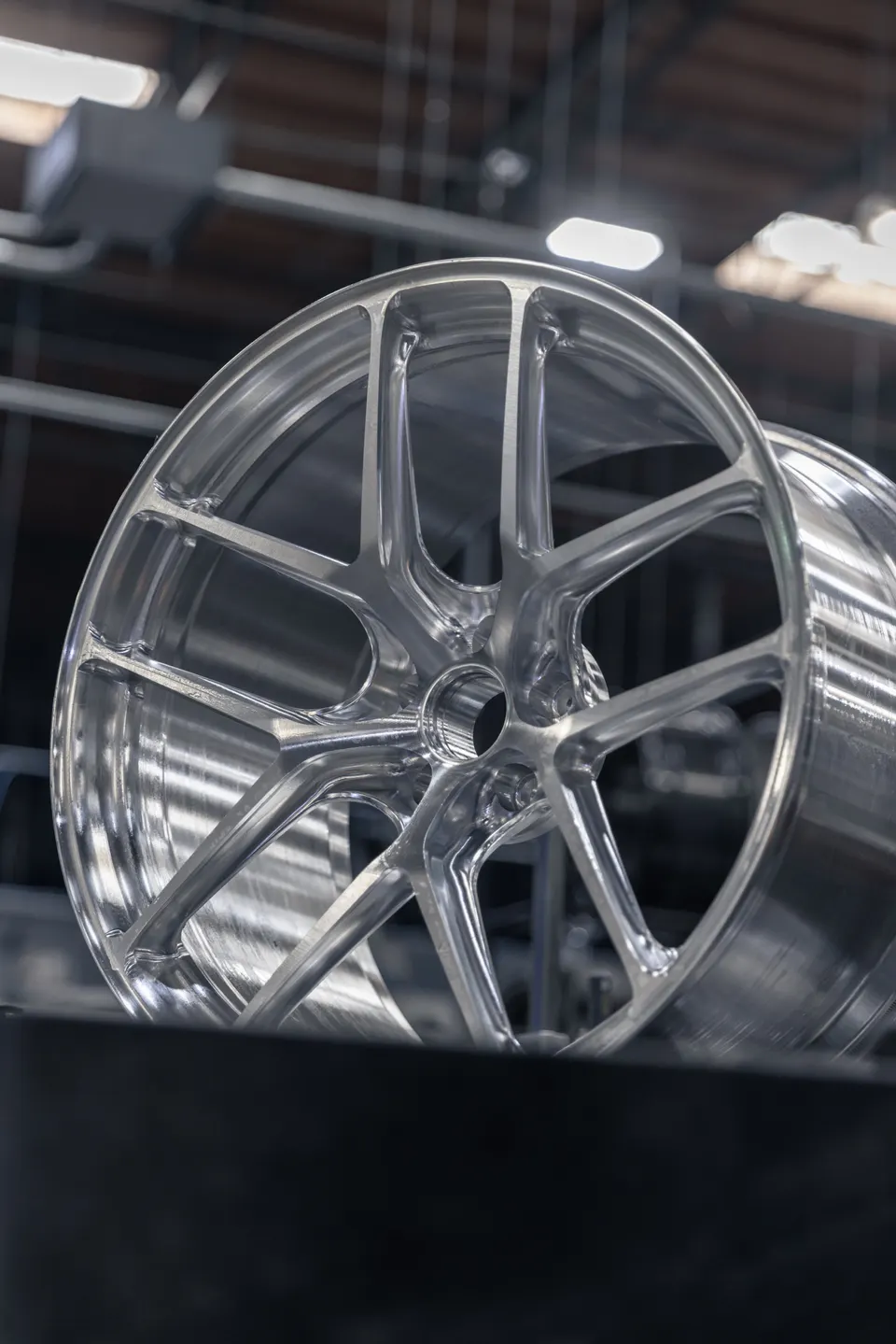 Close-up of a silver multi-spoke forged automotive wheel in a shop setting