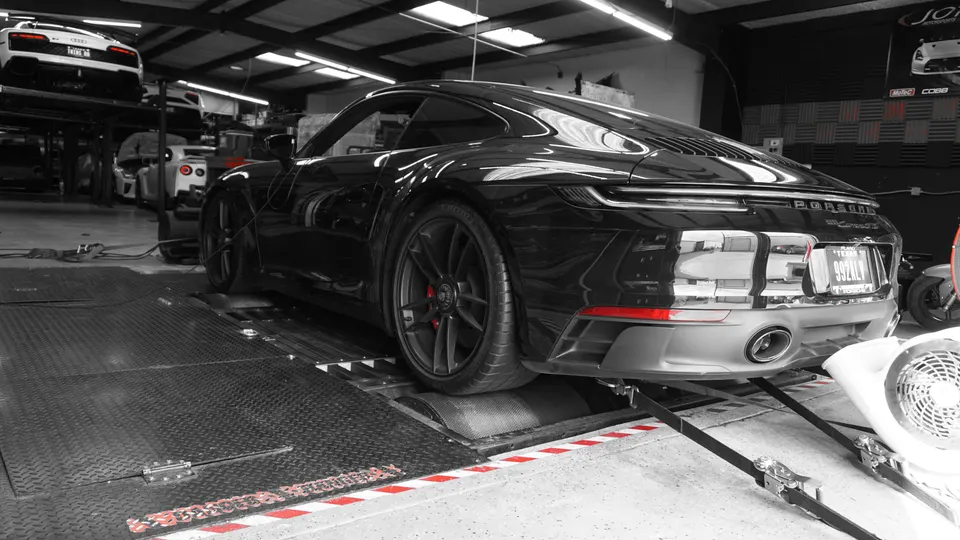 A black Porsche 911 strapped to a dyno for performance tuning at Jotech Motorsports.