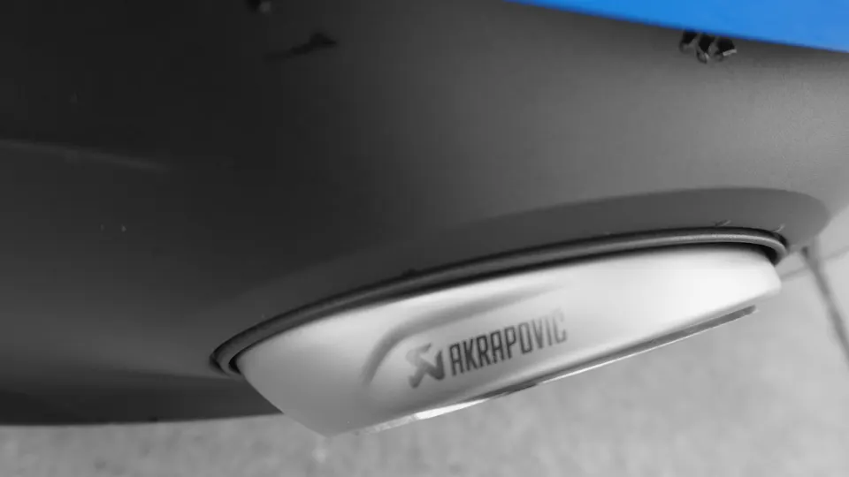 Close-up detail of an Akrapovic exhaust tip integrated into a car's rear bumper.